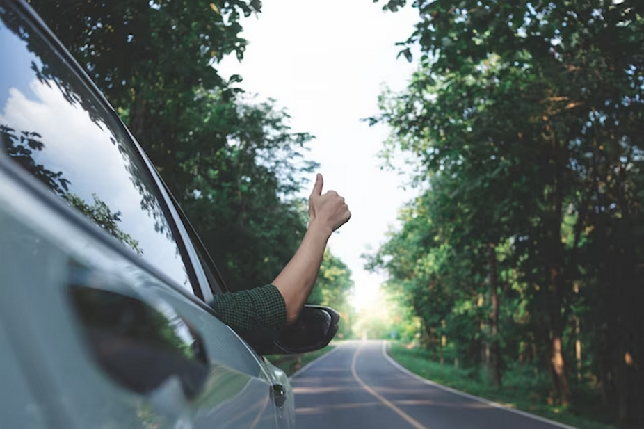 Car with driver giving a thumbs-up.